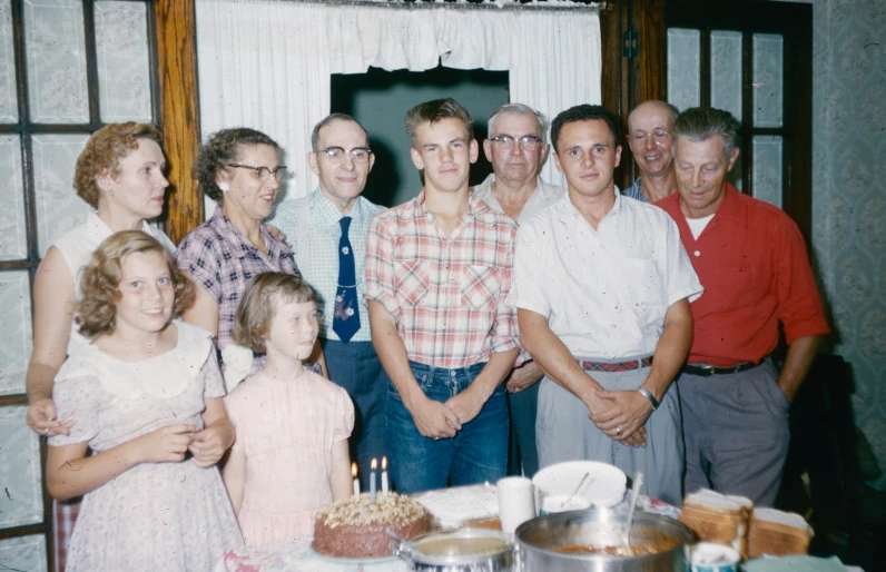 a group of people standing around a table with cake on it