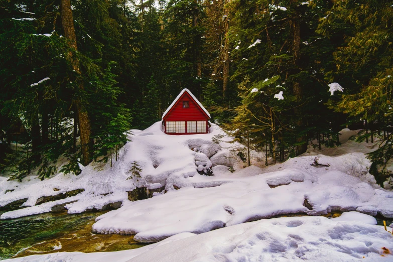 small cabin by the stream in the woods covered with snow