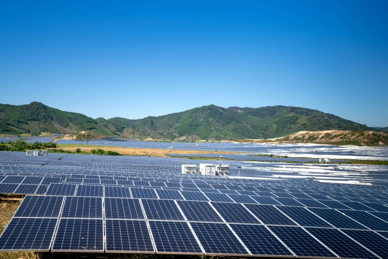 rows of solar panels sit on the ground at the bottom of a mountain