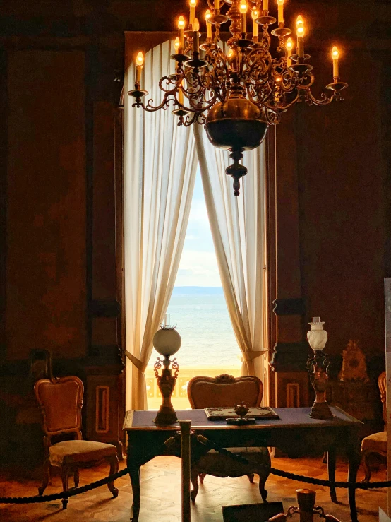 a dining table with a chandelier hanging from it and an open window