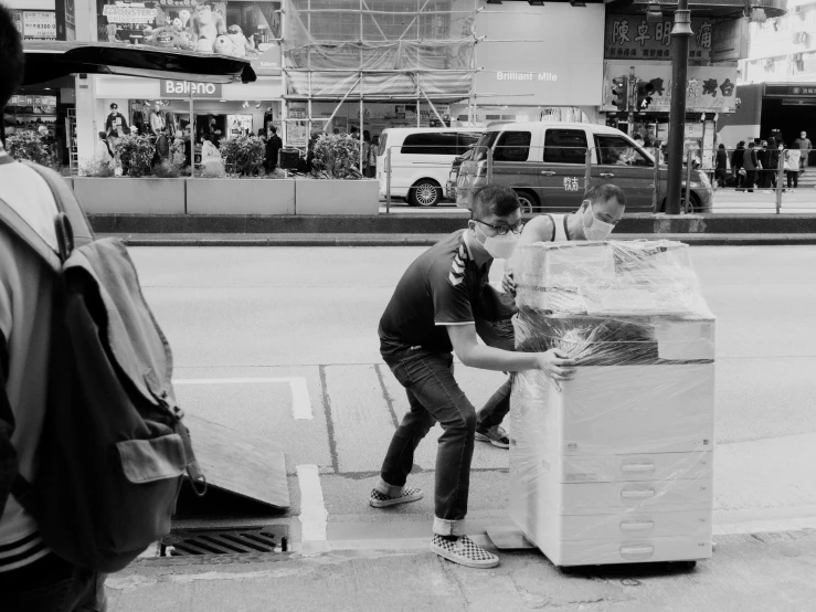 two boys hing a large pile of boxes down the street