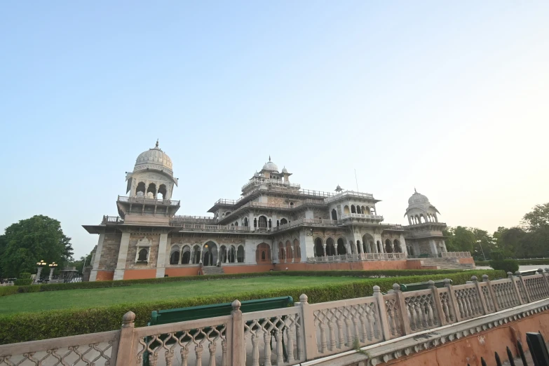 a long fence and a building that has an intricate design on the top