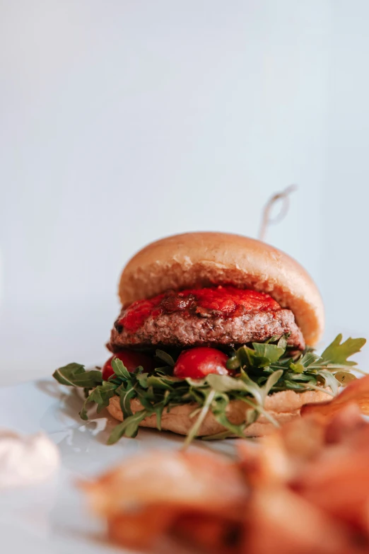 a hamburger with cheese, tomatoes, and arugula