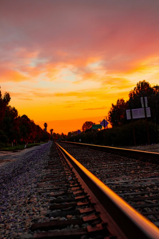 the sunset reflects on railroad tracks near a sign