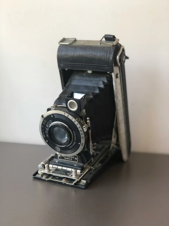 an old camera sits on top of a wooden table