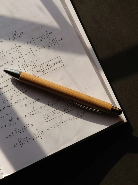 a wooden pen laying on top of paper with music diagrams