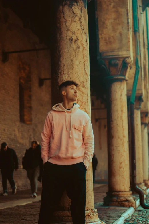 a man with a hoodie standing next to a column