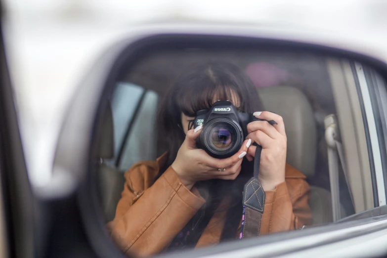 woman takes picture through mirror of car in traffic