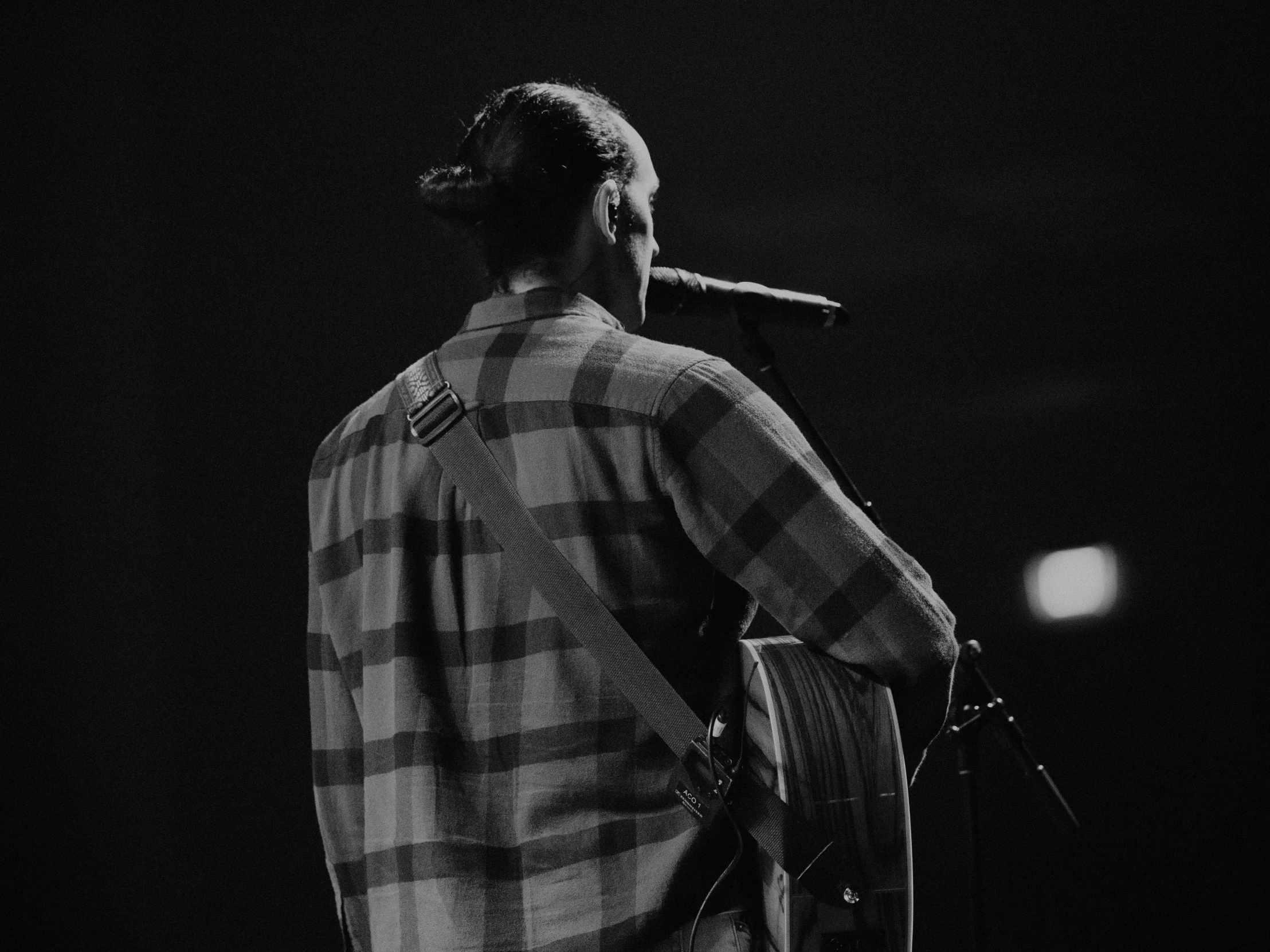 black and white pograph of a man on stage playing a guitar