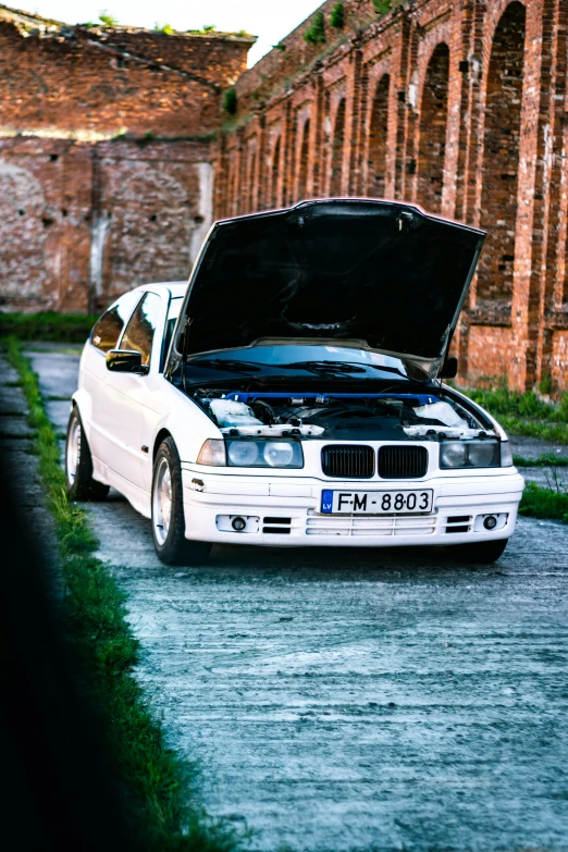 a car with a broken hood sitting on the side of the road