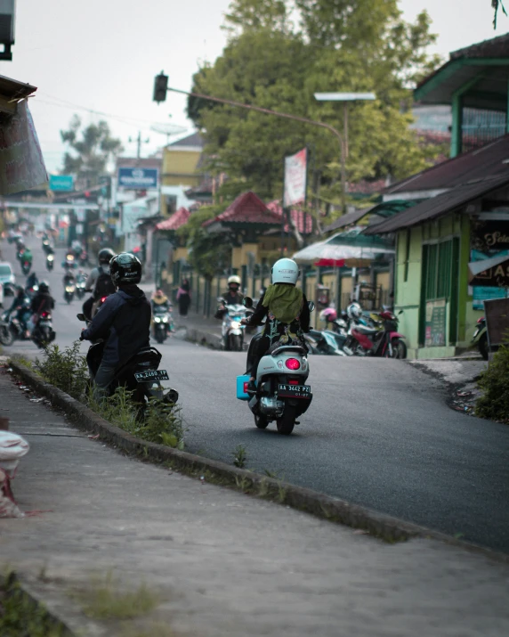 three people riding motorcycles on a street