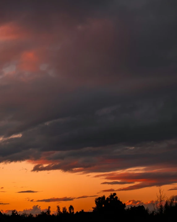 an airplane is flying away from a dark orange sunset