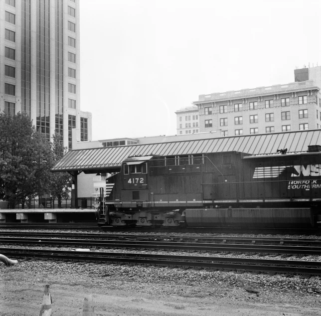 a train traveling past a tall building next to another train