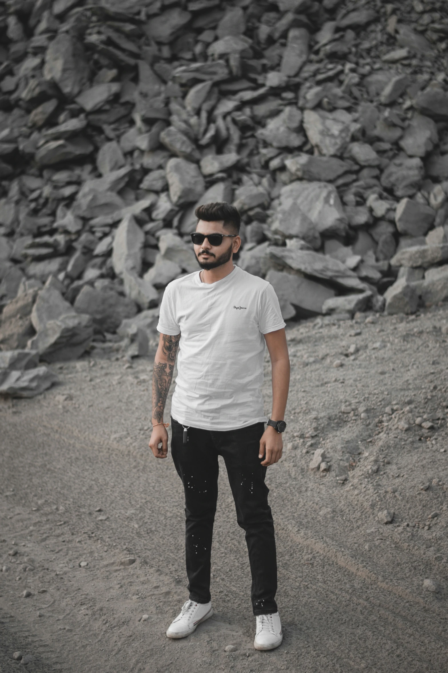 a man with tattoos stands in front of a rocky background