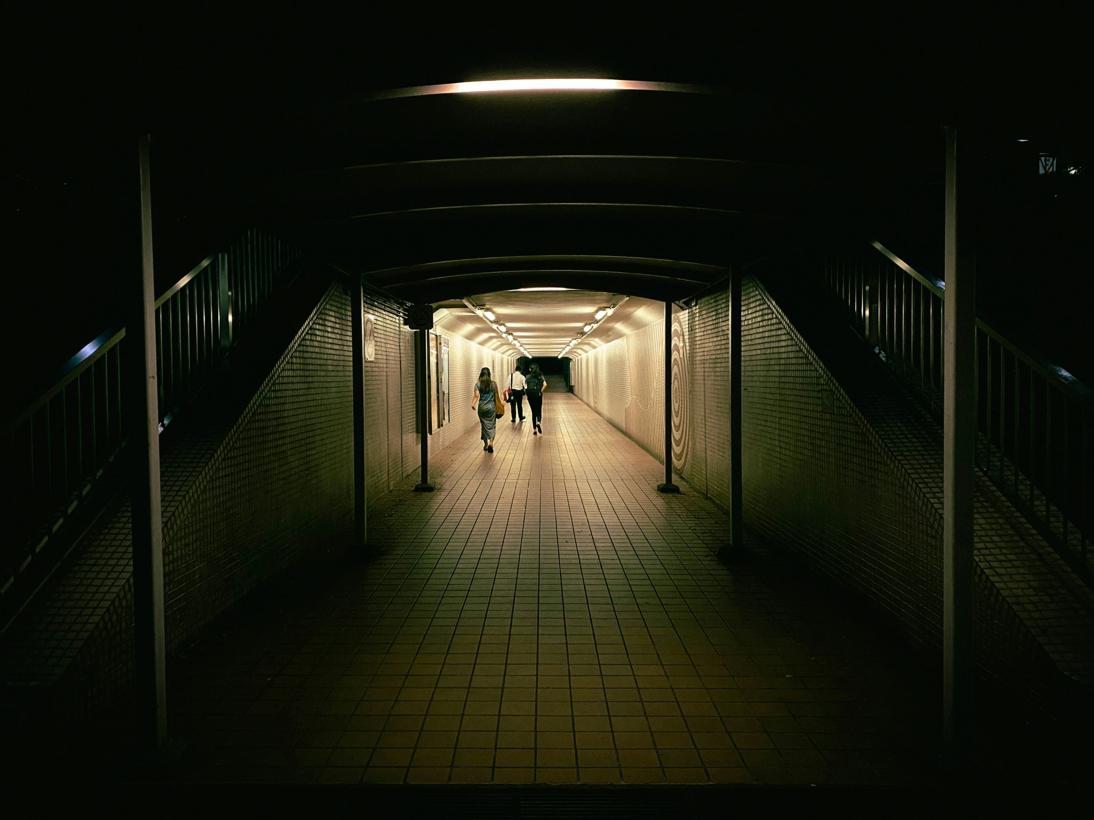 people walking in a dark tunnel that has no doors