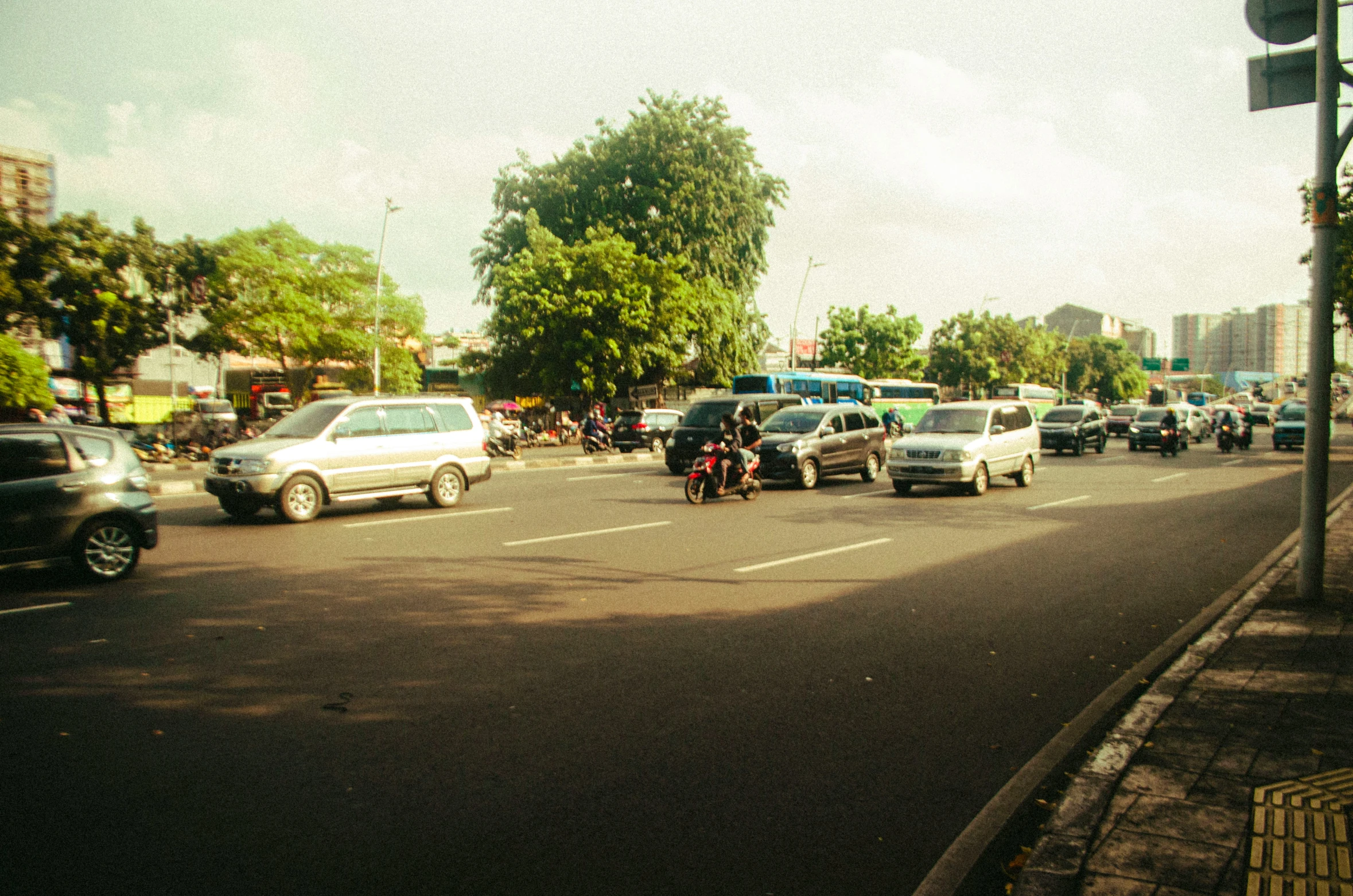 cars and motor bikes driving down a city street