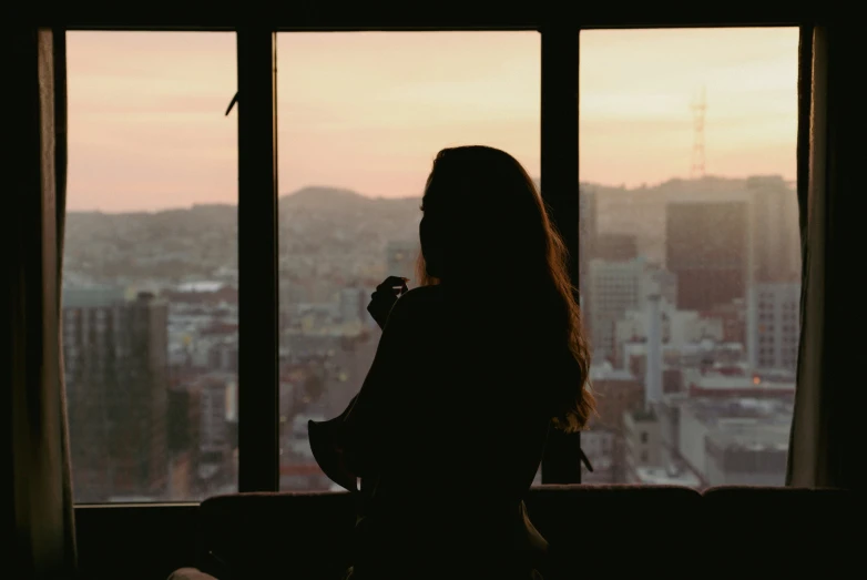 the silhouette of a woman facing a large window