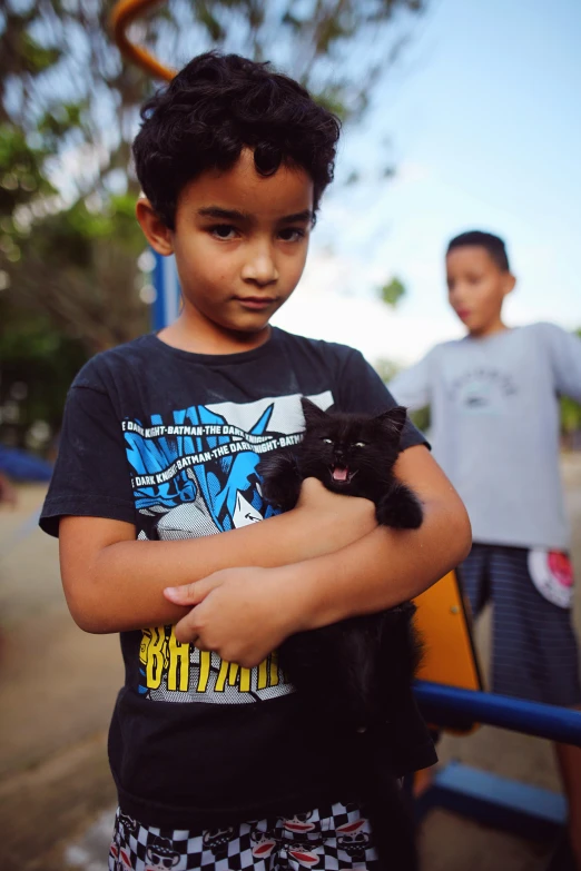  holding up black cat in front of him