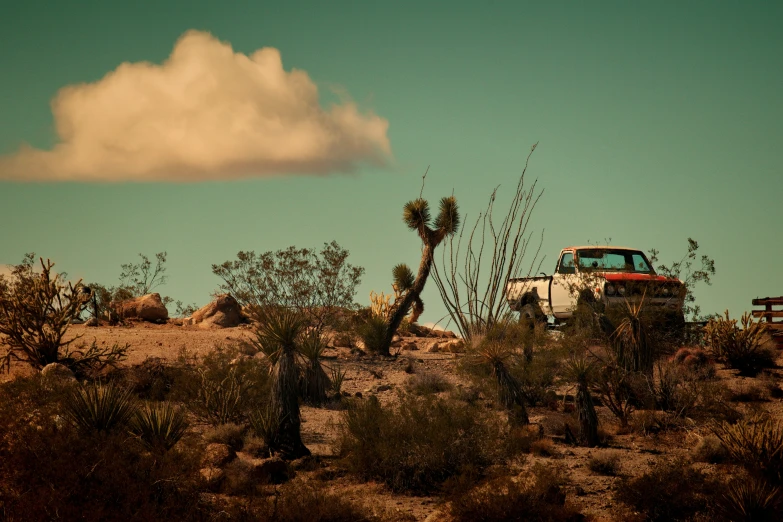 a vehicle sits on the desert, under a cloud