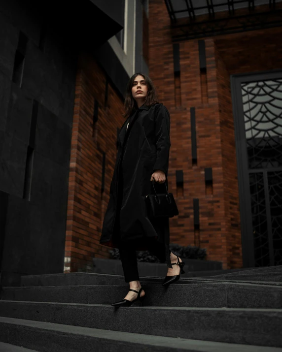 woman wearing a long coat and sandals posing on a stone steps