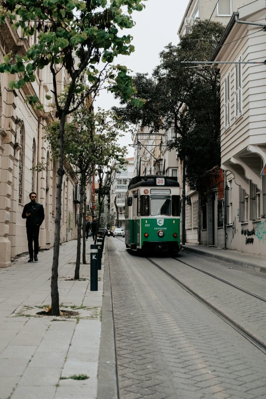 the tram is green and white in color on the street