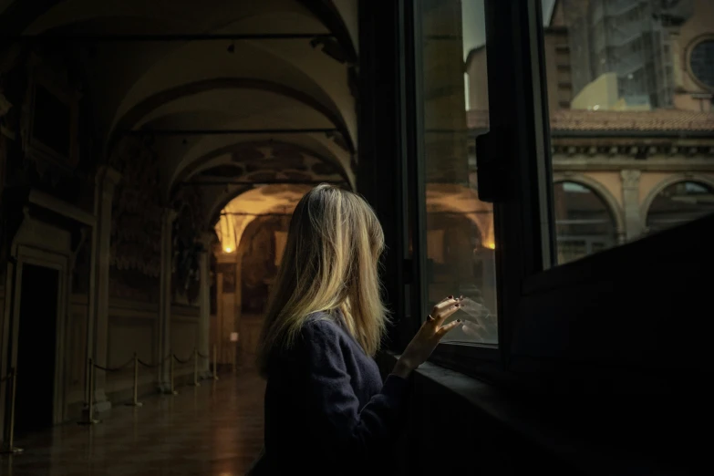 a woman looks out of the window while looking at her phone