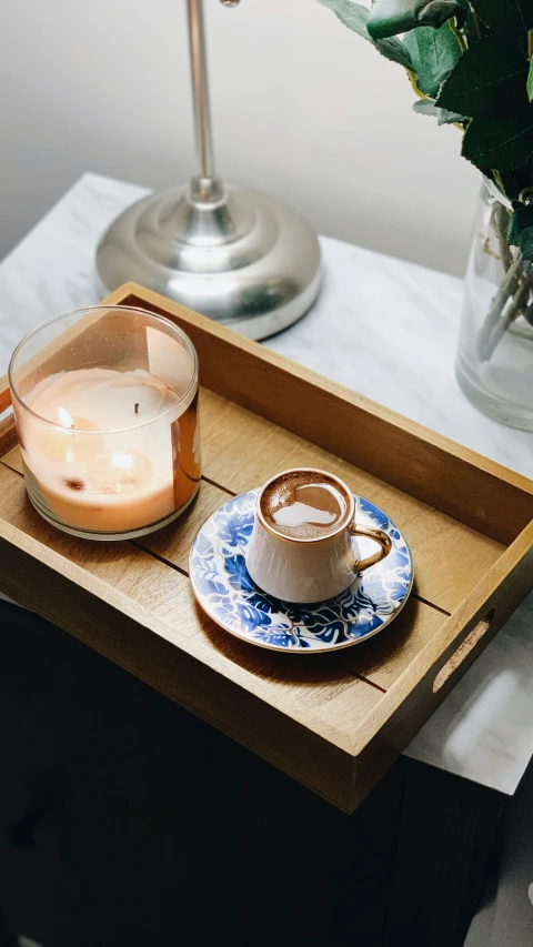 a small candle is sitting on a tray next to an empty coffee cup