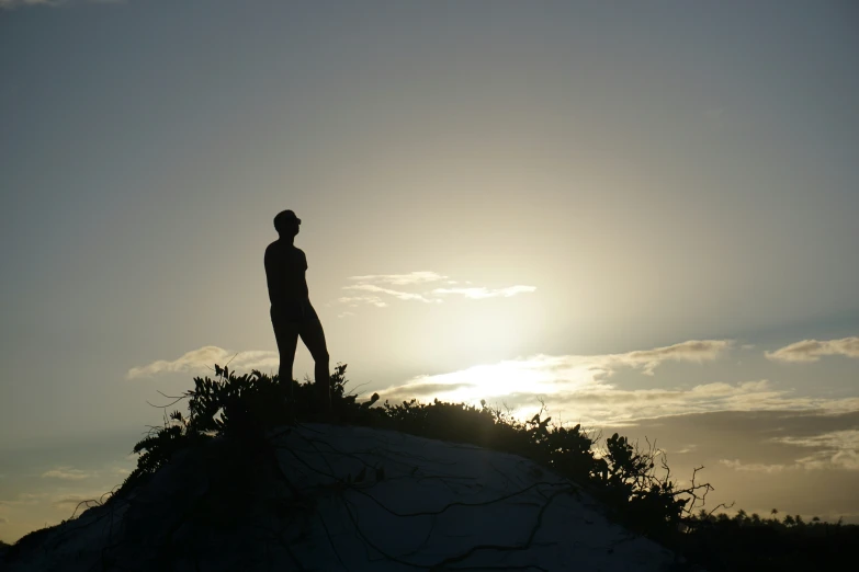 the silhouette of a man standing on top of a rock