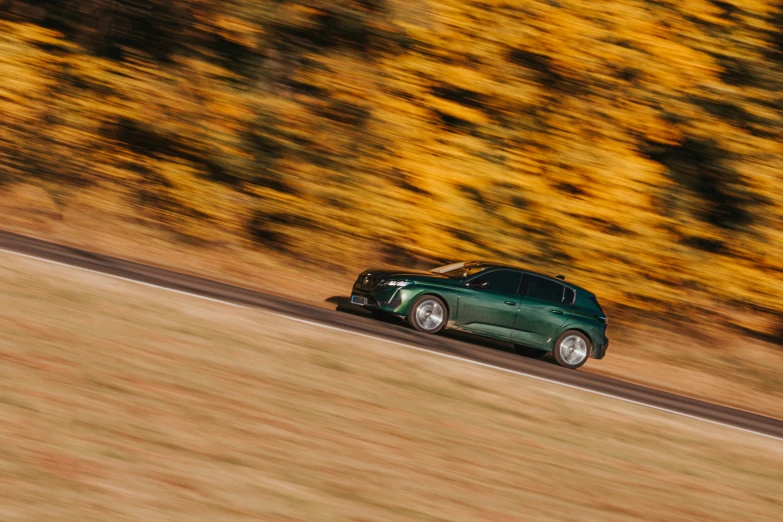 the green car is driving on the road with many orange trees