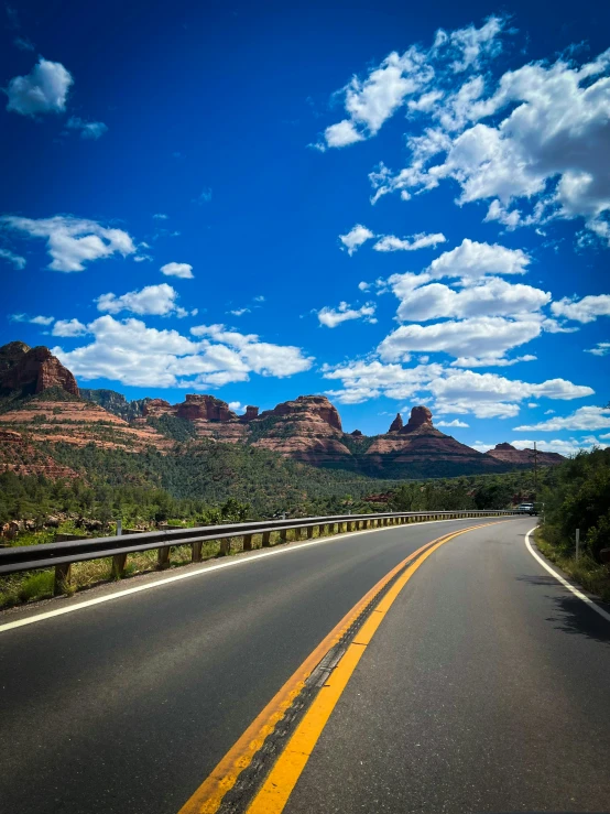 a road with yellow lines and mountains in the background