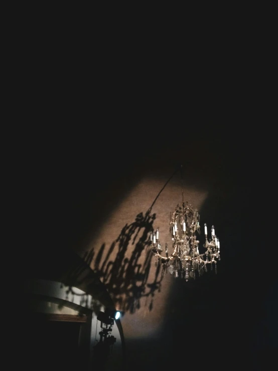 light shining on wall with ceiling and chandelier