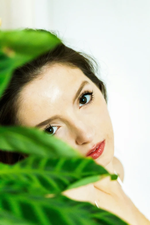 a woman smiles in between some green leaves