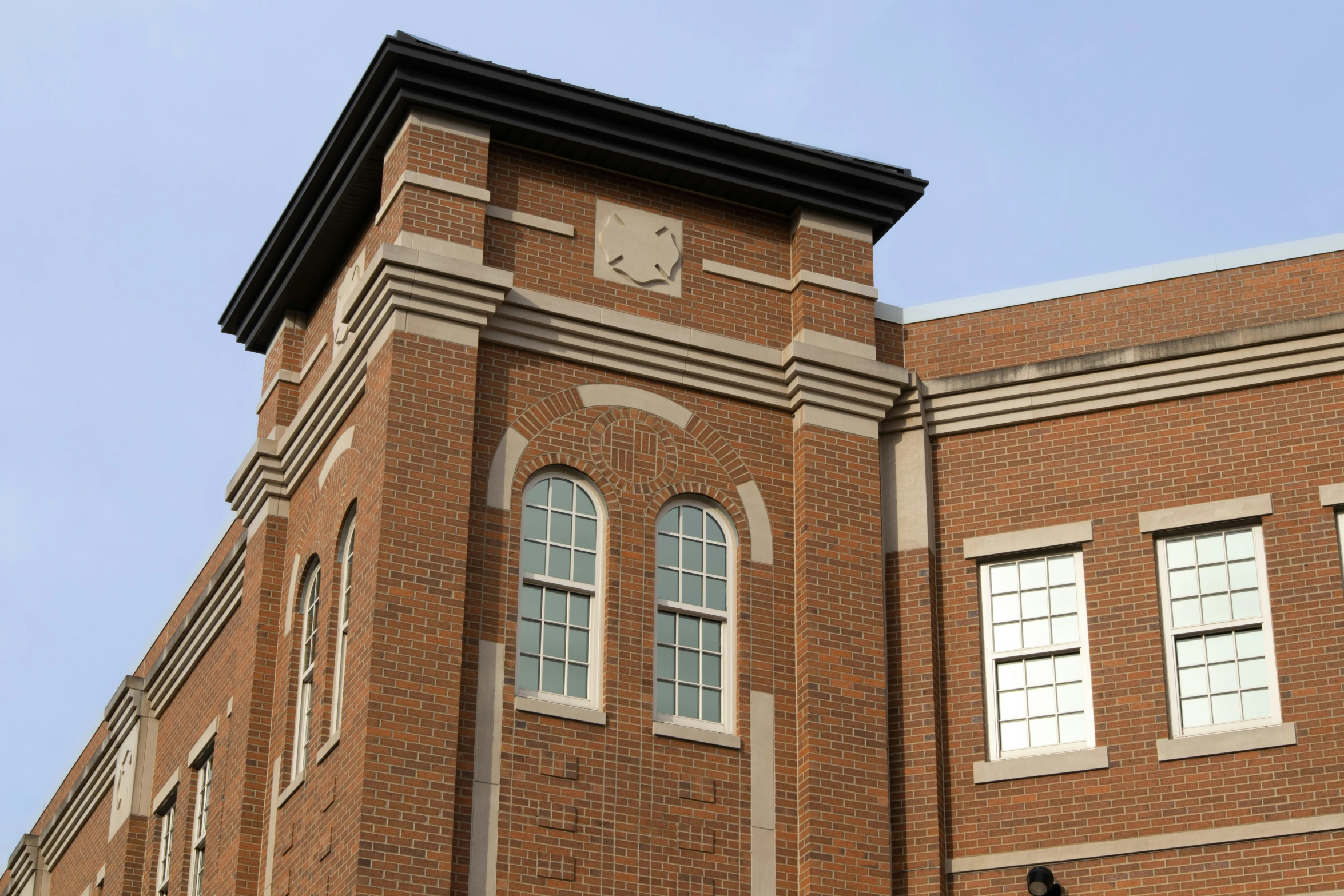 the corner of a tall building with three windows and a clock on the outside