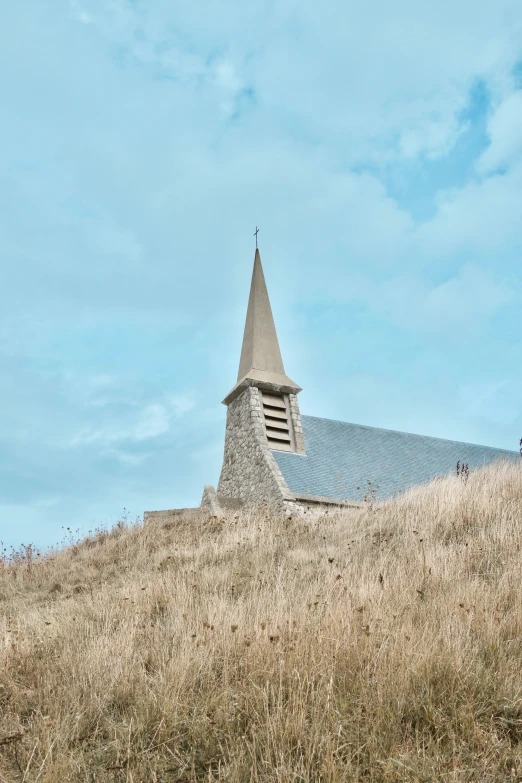 church on a hill with grass and blue sky in background