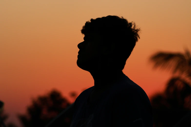 the silhouette of a man, head turned, at sunset