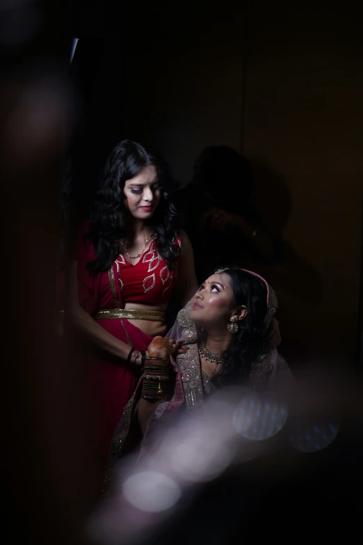 a woman standing near another woman in a dark room