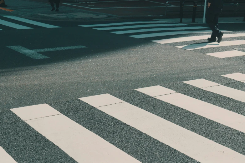 person walking across a cross walk while holding an umbrella