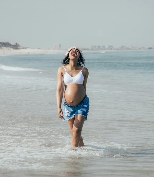 pregnant woman standing in the surf on a beach
