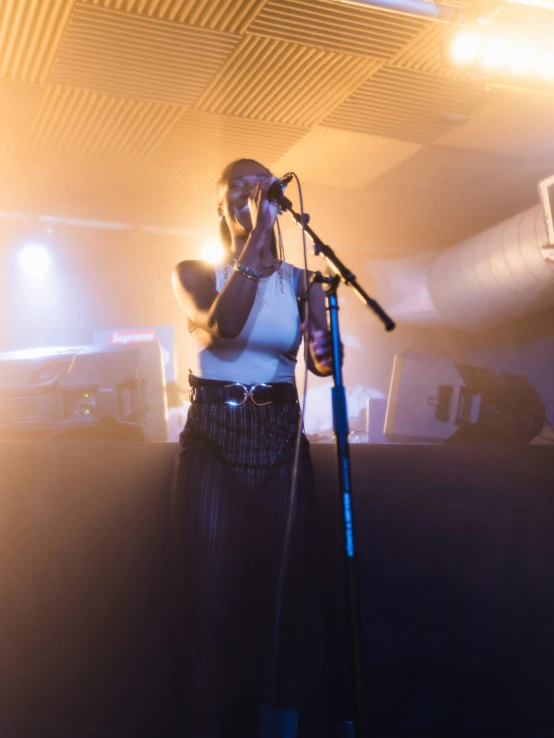 a woman standing on stage while singing into a microphone