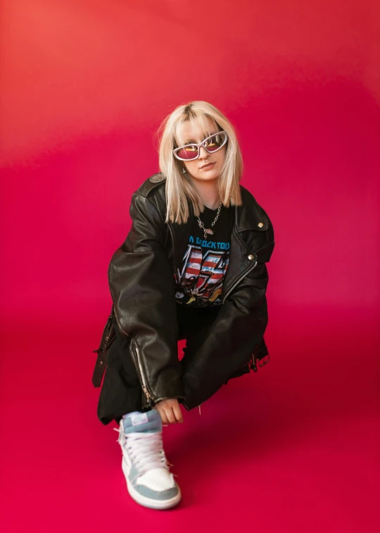 woman in black leather jacket sitting on a pink floor