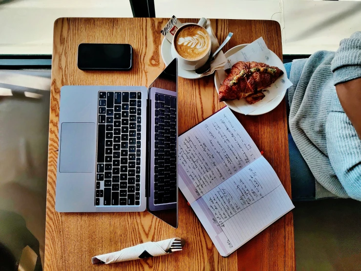 the table is covered with books, food and laptops