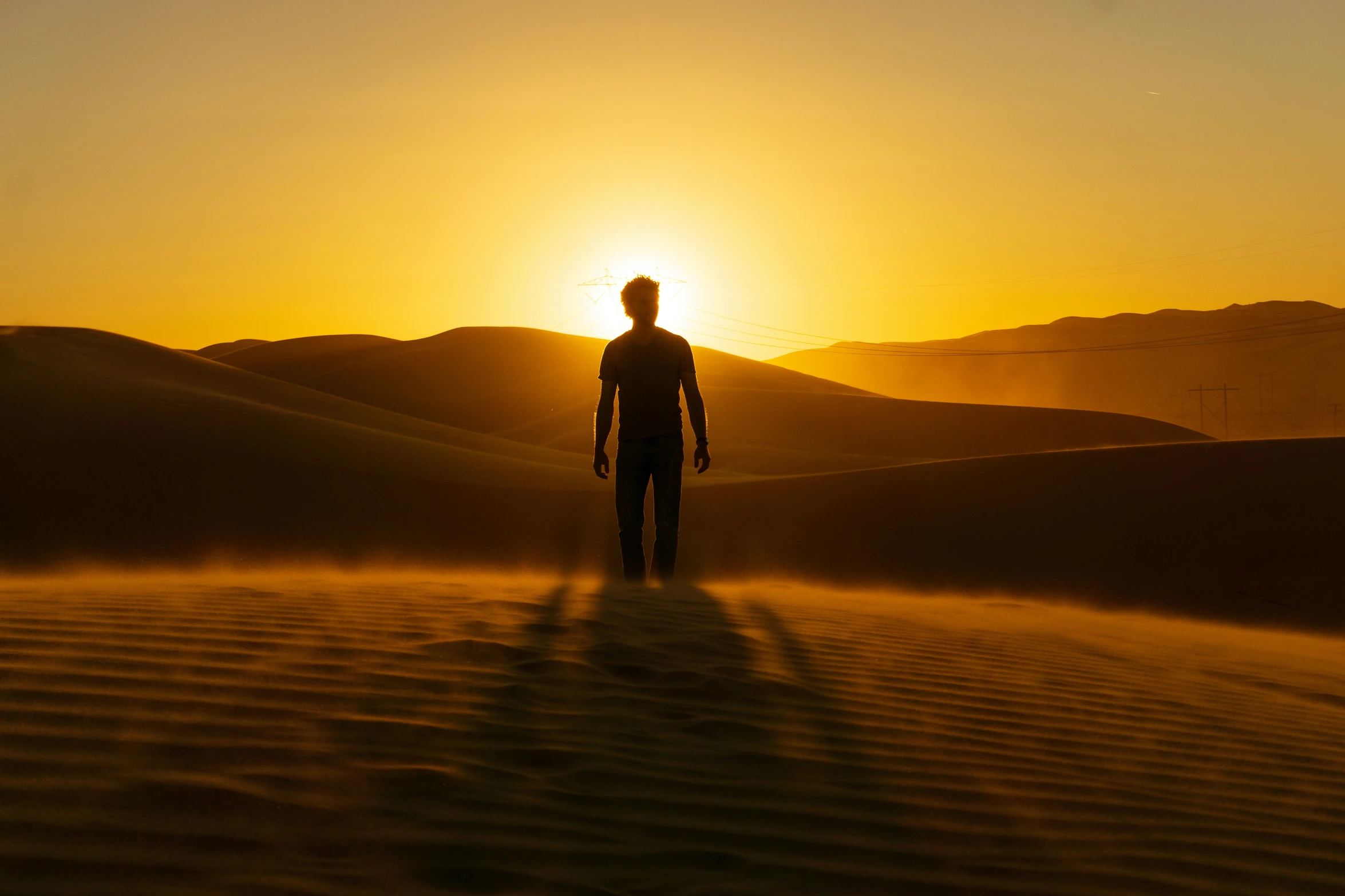 the person is standing in a desert at sunrise