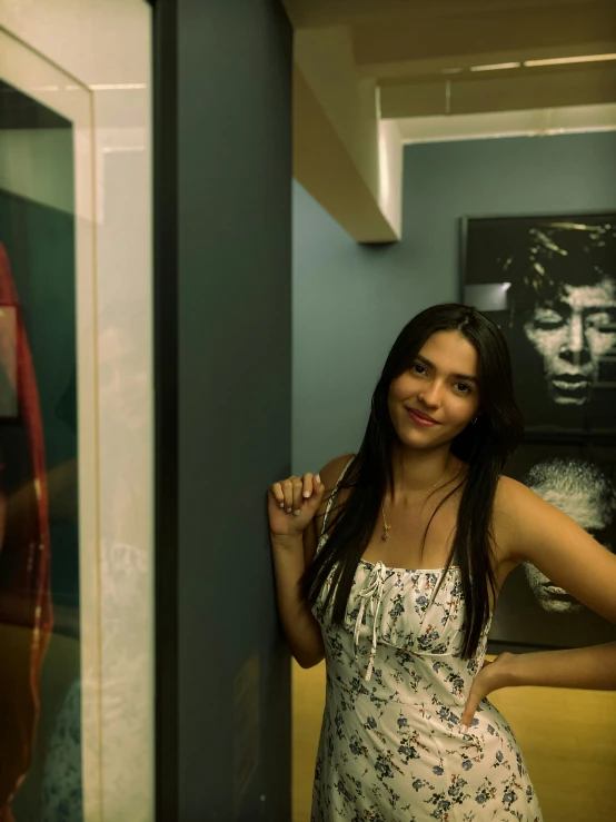 a beautiful woman wearing a white dress standing next to a glass