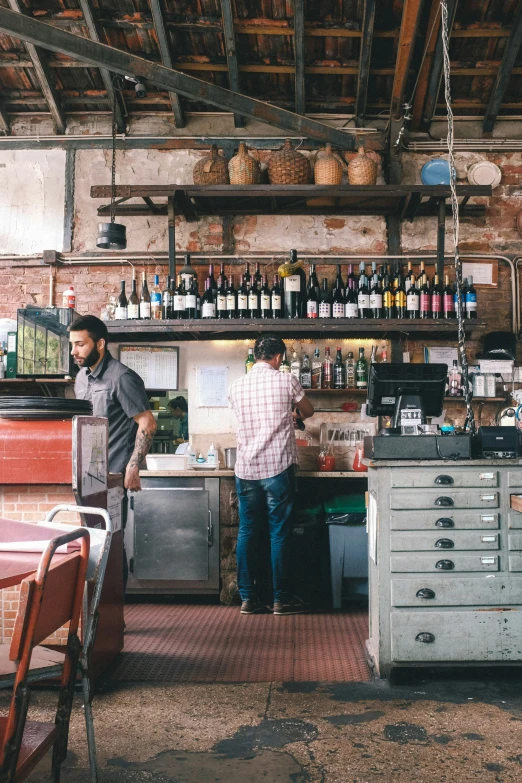 a couple of people standing behind a counter near shelves with bottles