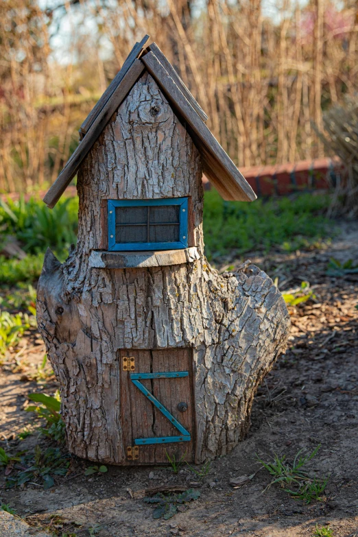 small tree house with window on log in grassy area