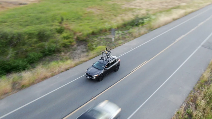 a truck driving on the side of the road with a luggage rack attached to the back of it