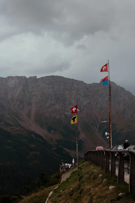 some flags waving high on a hill near the road