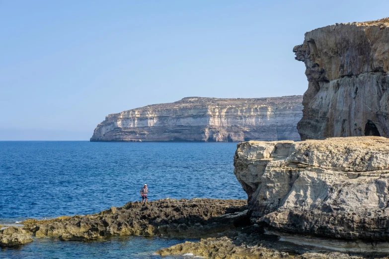 a person standing on rocks with the ocean near by