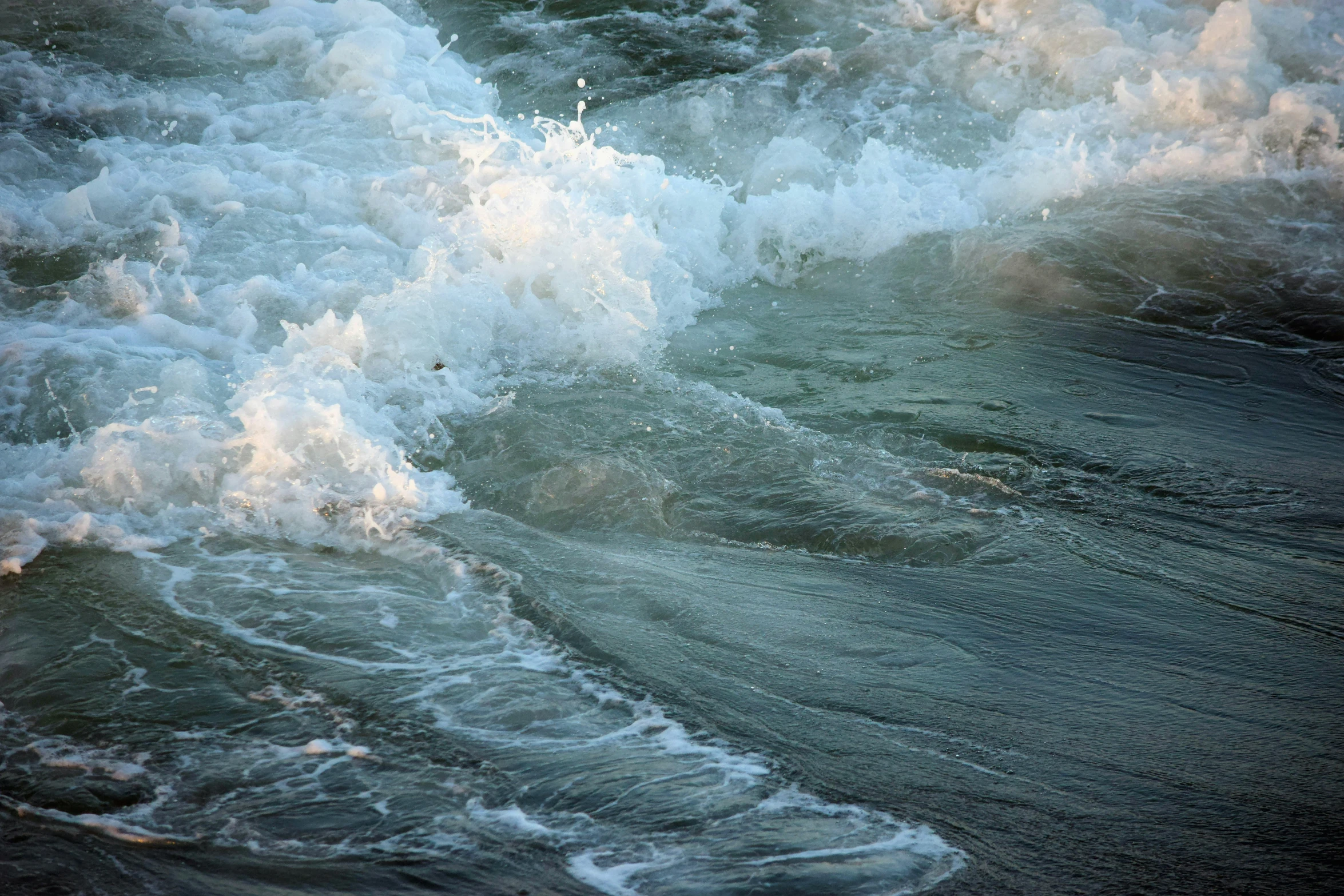 the white water crashes onto the sandy beach