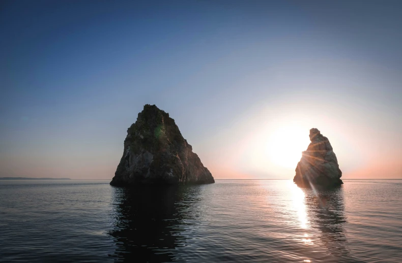 a large rock in the water next to a body of water